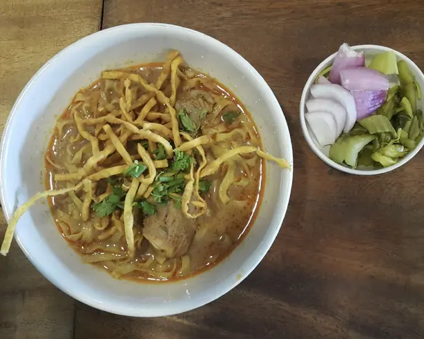 Foto von Khao Soi - Nordthailändische Curry-Nudelsuppe mit Knusper-Topping – fertig angerichtet